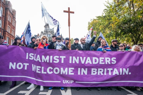 A group of people stand behind a banner stretched across a road reading 'Islamist invaders not welcome in Britain'.