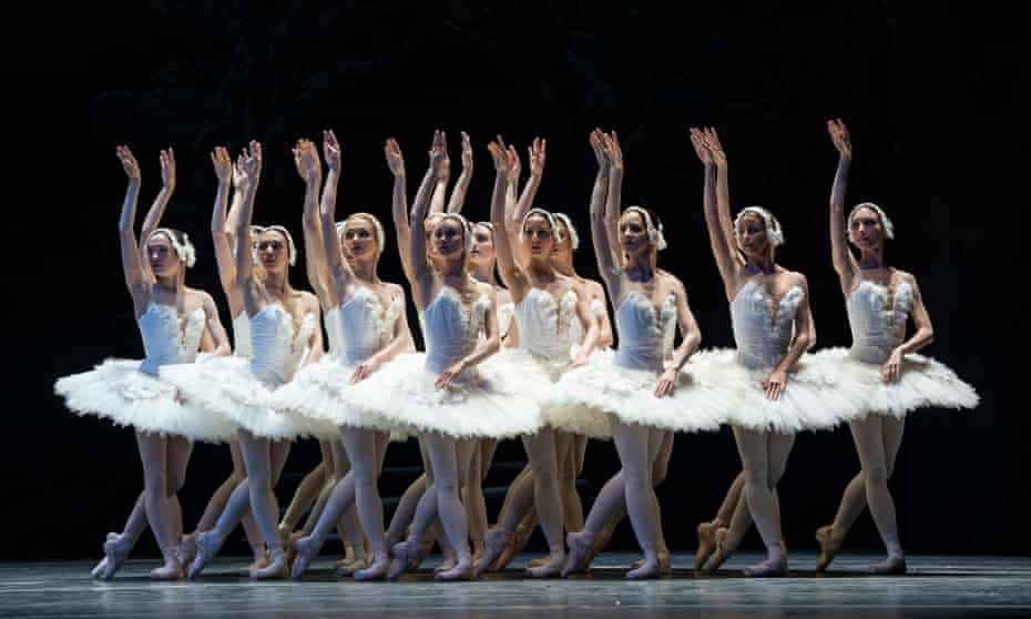 A group of ballet dancers mid-performance in traditional white tutus