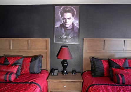 beds with red sheets and a poster of edward