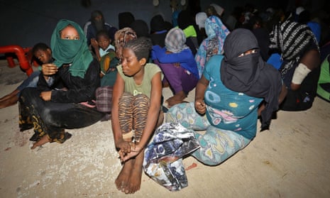 Migrants seated on dusty floor