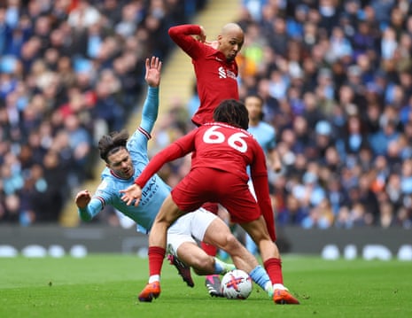 Manchester City’s Jack Grealish goes down under a challenge by Liverpool's Fabinho as Trent Alexander-Arnold looks on.