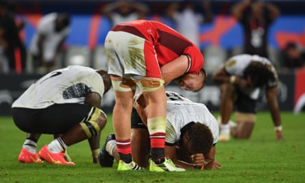 Fiji players (in white) on the turf after losing against Wales.