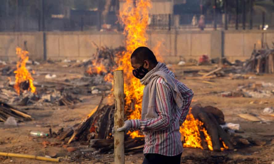 A man walks past burning funeral pyres of people, who died from Covid.