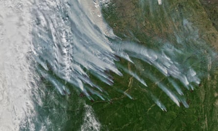 A satellite image showing large clouds of smoke spreading over forest