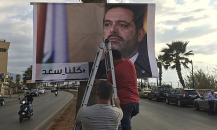 Workers hang a poster of outgoing prime minister Saad Hariri with the Arabic words ‘We are all Saad’ in Beirut.