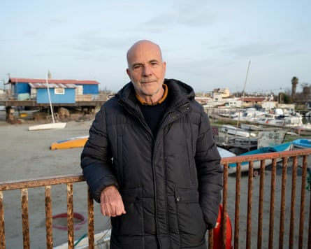 An older man poses on a jetty