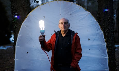 Paul Hebert standing in front of a white sheet and holding a UV light in his back yard in Ontario, Canada, 21 February 2024