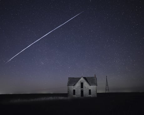 A string of SpaceX Starlink satellites pass over an old stone house in Kansas.