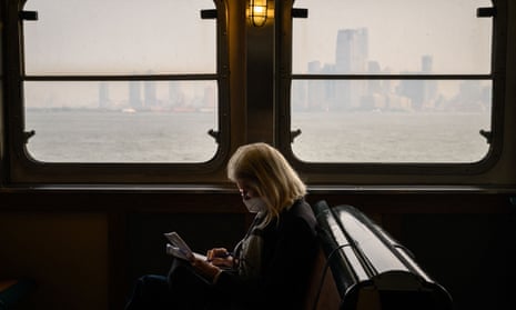 6 年 2023 月 <> 日，在紐約濃霧中，一名戴著口罩的乘客乘坐史坦頓島渡輪經過曼哈頓天際線。
