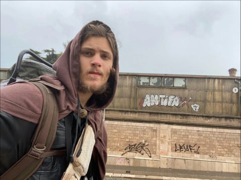 Young man with backpack wearing hoodie taking selfie and looking seriou s