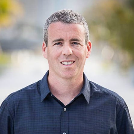 A man wearing a blue shirt smiling for a photo.