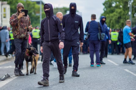 Young man in black clothes and balaclavas among police and protesters
