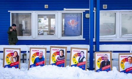 A man gestures behind posters for the Greenlandic political party Siumut outside their office in Nuuk, Greenland, on 6 March.
