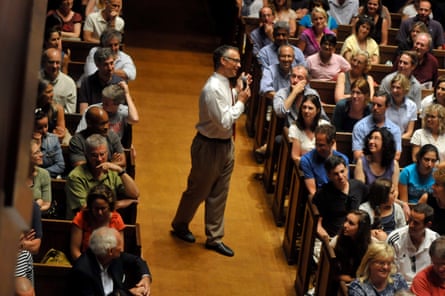 man smiles as he walks down aisle between groups of parents