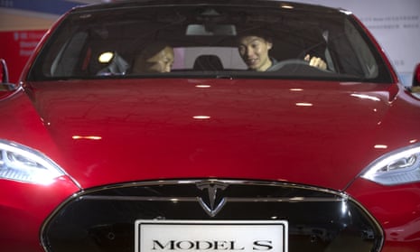 A man behind the steering wheel of a Tesla Model S electric car at the Beijing international automotive exhibition in 2016