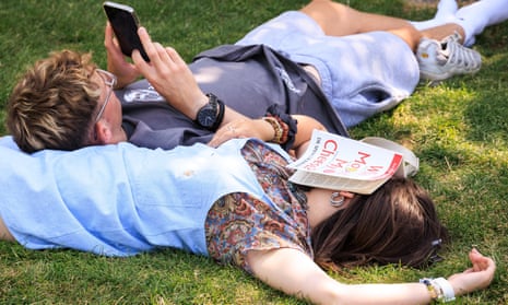 couple lying on grass, woman with book over face