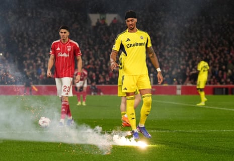 Archie Brown removes a flare thrown on the pitch by the away supporters.
