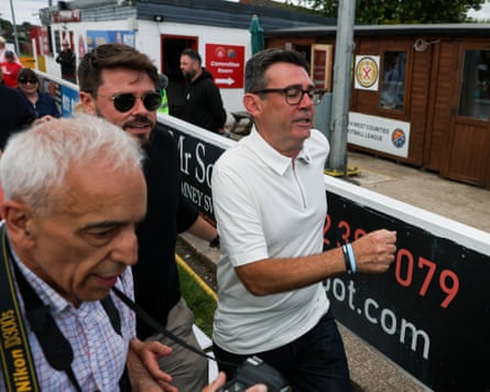 Burnham walking past advertising hoardings at the football ground