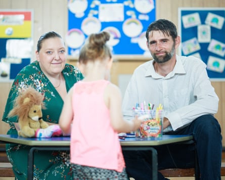 Parents sit at a table full of toys as their daughter plays with them