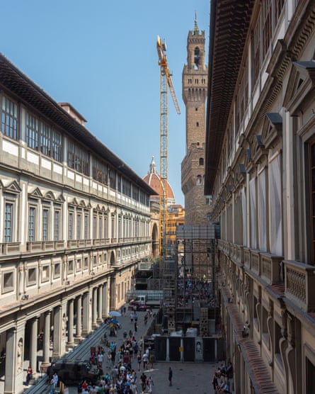 Narrow street view with buildings either side with crane in background against blue sky