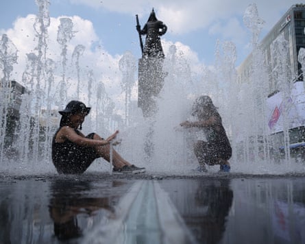 Two children playing in the water of a pavement fountain