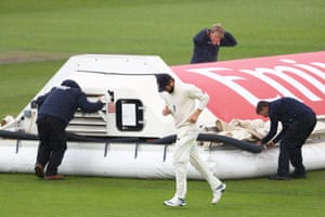 Woakes makes his way off whilst the ground staff put the covers on.