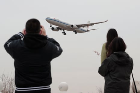 People look at a plane preparing to land at Beijing Capital airport in China