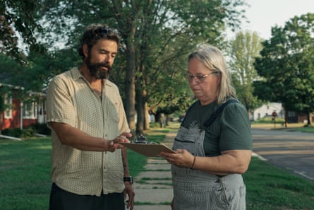 Man and woman look at a clipboard on a grassy sidewalk.