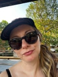 Maria, 37 – she has long blond hair and wears large black sunglasses, a black cap and red lipstick as she looks into the camera
