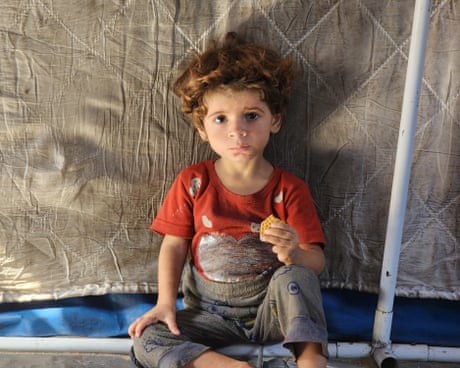 Small child holding a small biscuit and looking sad