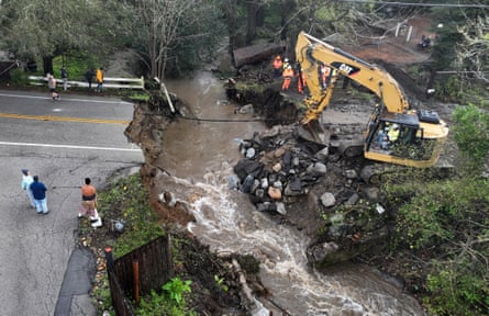 Workers make emergency repairs to a road that was washed out heavy rains on March 10, 2023 in Soquel, California.