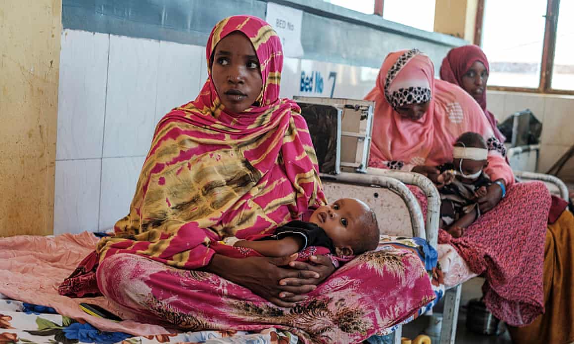Women and children sit in a hospital.