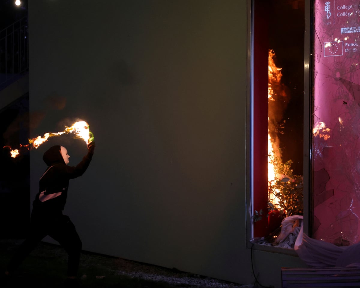 A masked protester throws a petrol bomb at the College of Europe building during clashes in Tirana.