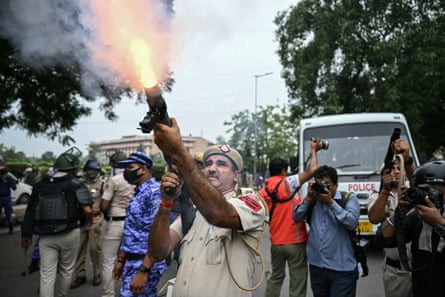 Smoke and flame fires from the muzzle as a male police officer shoots a teargas shell