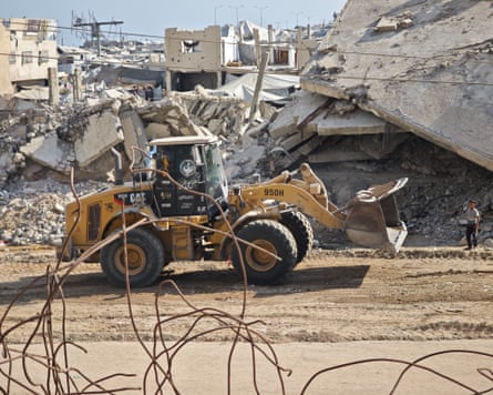 A digger driving past rubble in Gaza City.