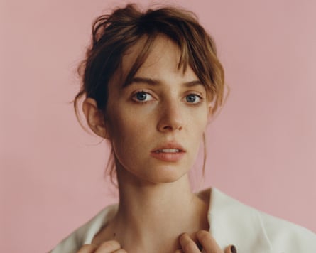 Maya Hawke looking at the camera against a pink backdrop.