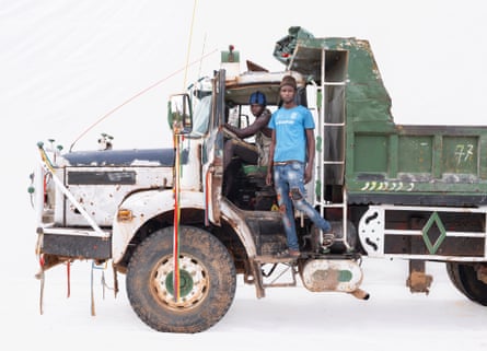 Truck driver Moustapha with assistant Boubacar in a Berliet truck in Nguékhokh, Senegal. Moustapha is sat in the cab of the truck and Boubacar on the step up to the cab