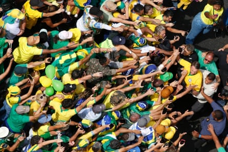 Aerial view of people reaching their arms towards Jair Bolsonaro