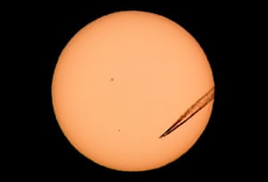 A jet leaves a vapour trail as Mercury, the black dot lower left of the centre of the sun, is seen from Las Vegas