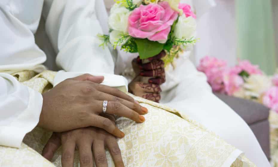 The hands of a bride and groom during a wedding ceremony.