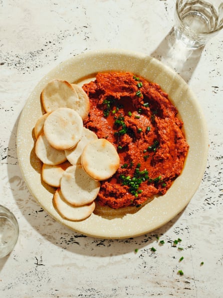 Topview of a round plate with a vibrant tomato tuna dip sprinkled with herbs, and water crackers.