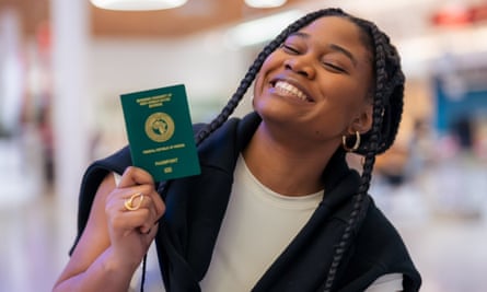 A young African woman smiles as she holds up a Nigerian passport