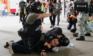 A Hong Kong police officer brandishes his pepper spray handgun as he arrests a protester.