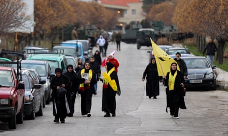 Women walk and hold flags in Burj al-Muluk, near the southern Lebanese village of Kfar Kila, where Israeli forces remained on the ground.