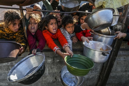 Small children holding out metal and plastic bowls