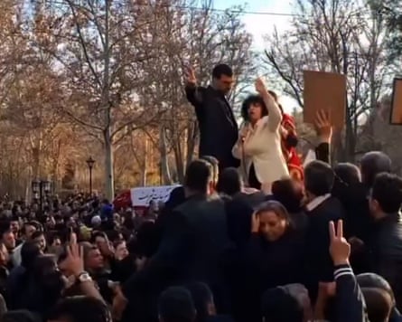 A woman addresses a crowd from a raised position