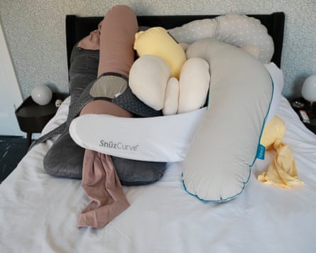 A selection of pregnancy pillows piled on a bed