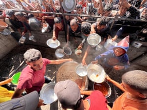 An aerial image of people holding empty bowls around a pot of hot food