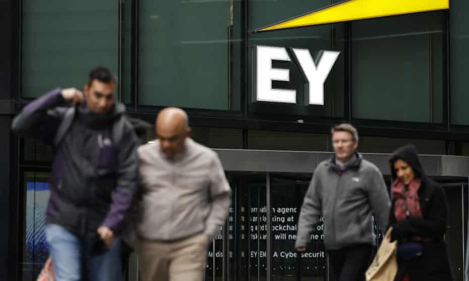 Pedestrians walk past the offices of accounting and auditing firm EY.