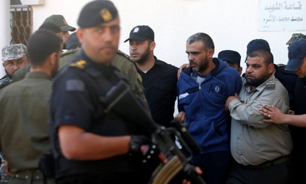 Palestinian security forces escort one of the men convicted of participating in the killing of Mazen Faqha